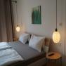 A modern bedroom with double bed, two hanging lamps and a small table with remote control.