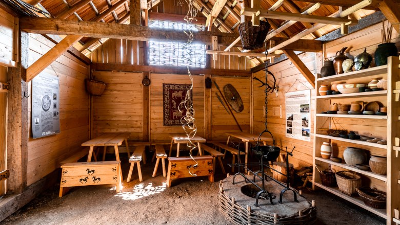 Interior view of a reconstructed Celtic house with wooden furniture and pottery.