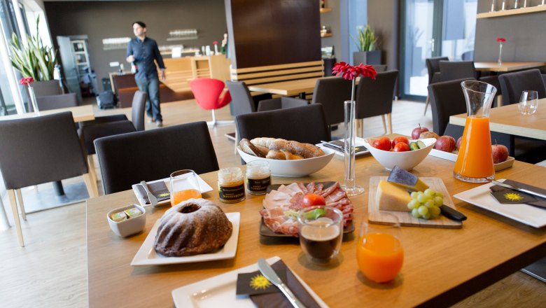 Breakfast table with pastries, cold cuts, cheese, fruit and juice in a modern café.