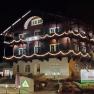 An illuminated building called Schneeberghof at night, decorated with fairy lights.