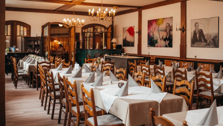 A cozy dining room with wooden furniture, laid tables and chandeliers.