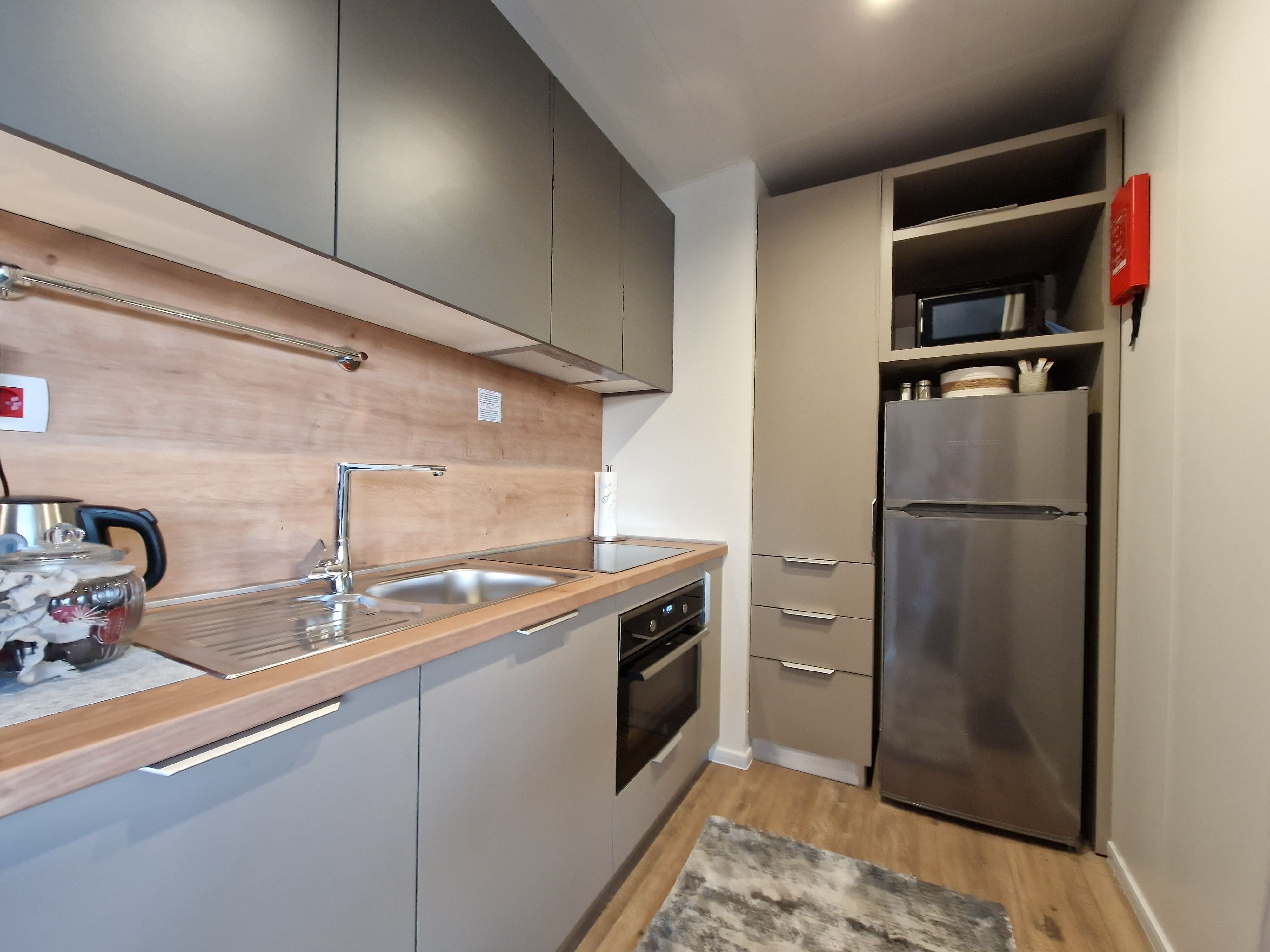 Modern kitchen with gray cabinets, stainless steel sink, stove and refrigerator.