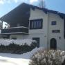 A snow-covered house with wooden balcony and 'Haus Almboden' sign.
