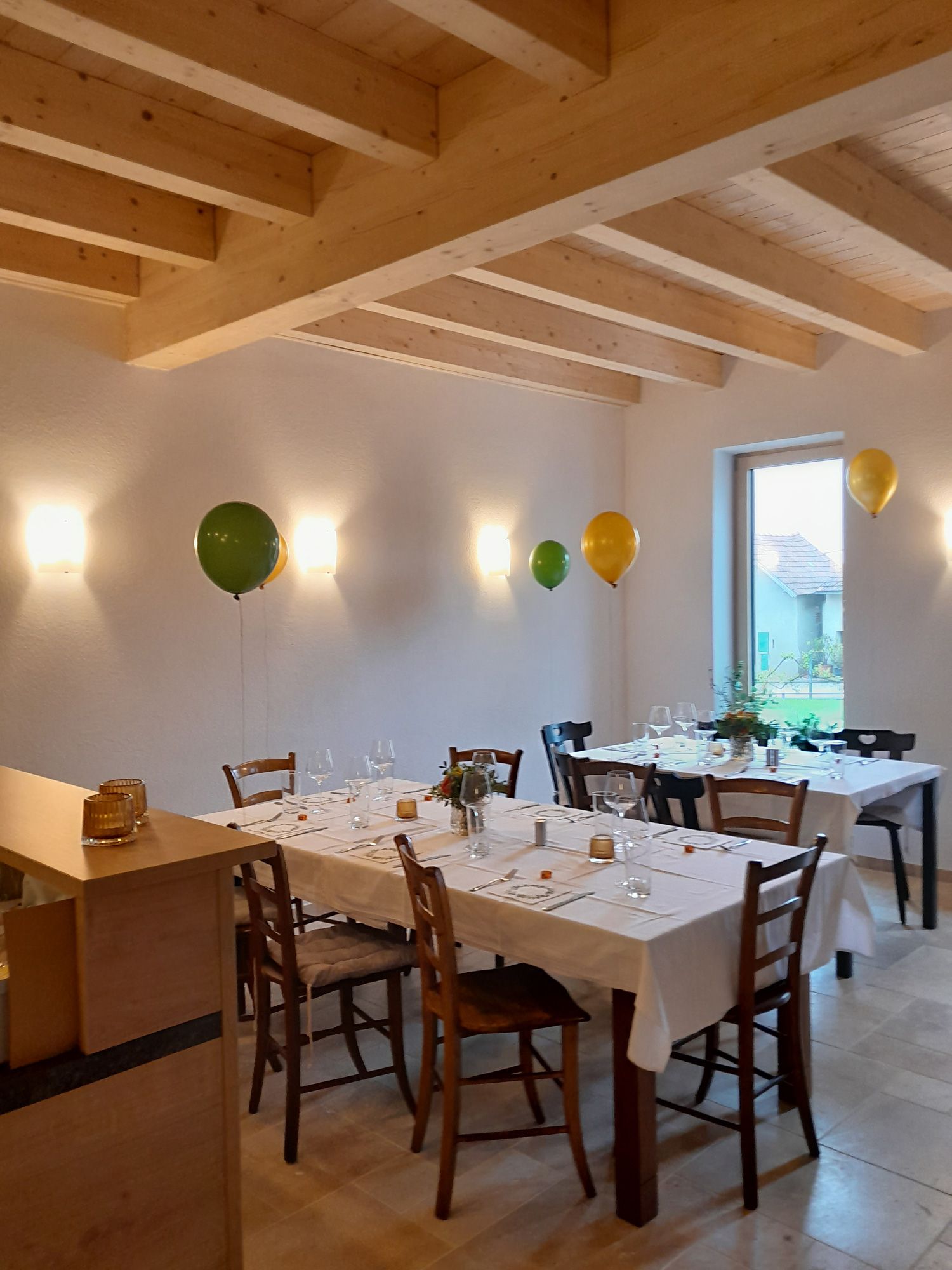 A festively laid table in a room with a wooden beamed ceiling and balloons on the wall.
