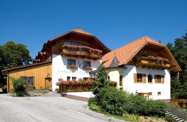 A traditional country inn with a wooden façade and flower boxes under a blue sky.