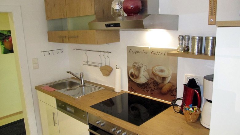 Modern kitchen with wooden worktop, stove, sink and coffee machine.