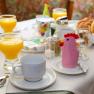 Breakfast table with orange juice, bread rolls and cups in a guesthouse.