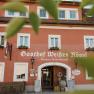 Facade of the Weißes Rössl inn in Mühldorf with red wall and white windows.