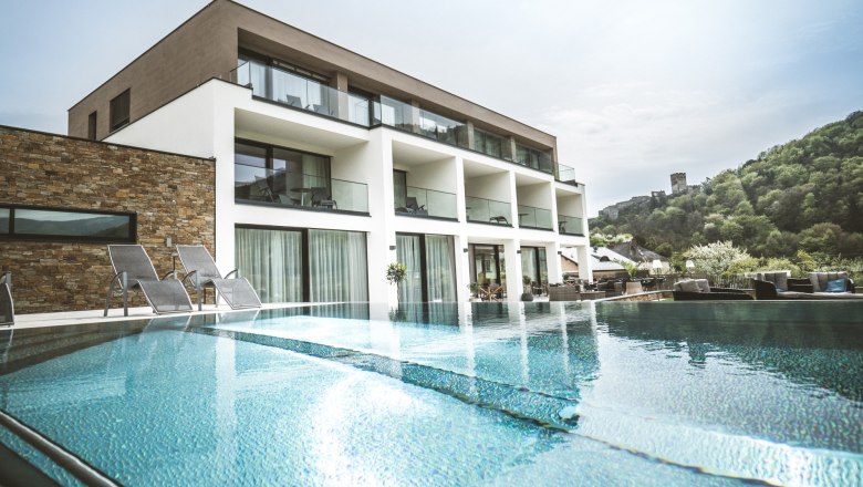 Modern boutique hotel with pool and sun loungers, surrounded by green countryside.