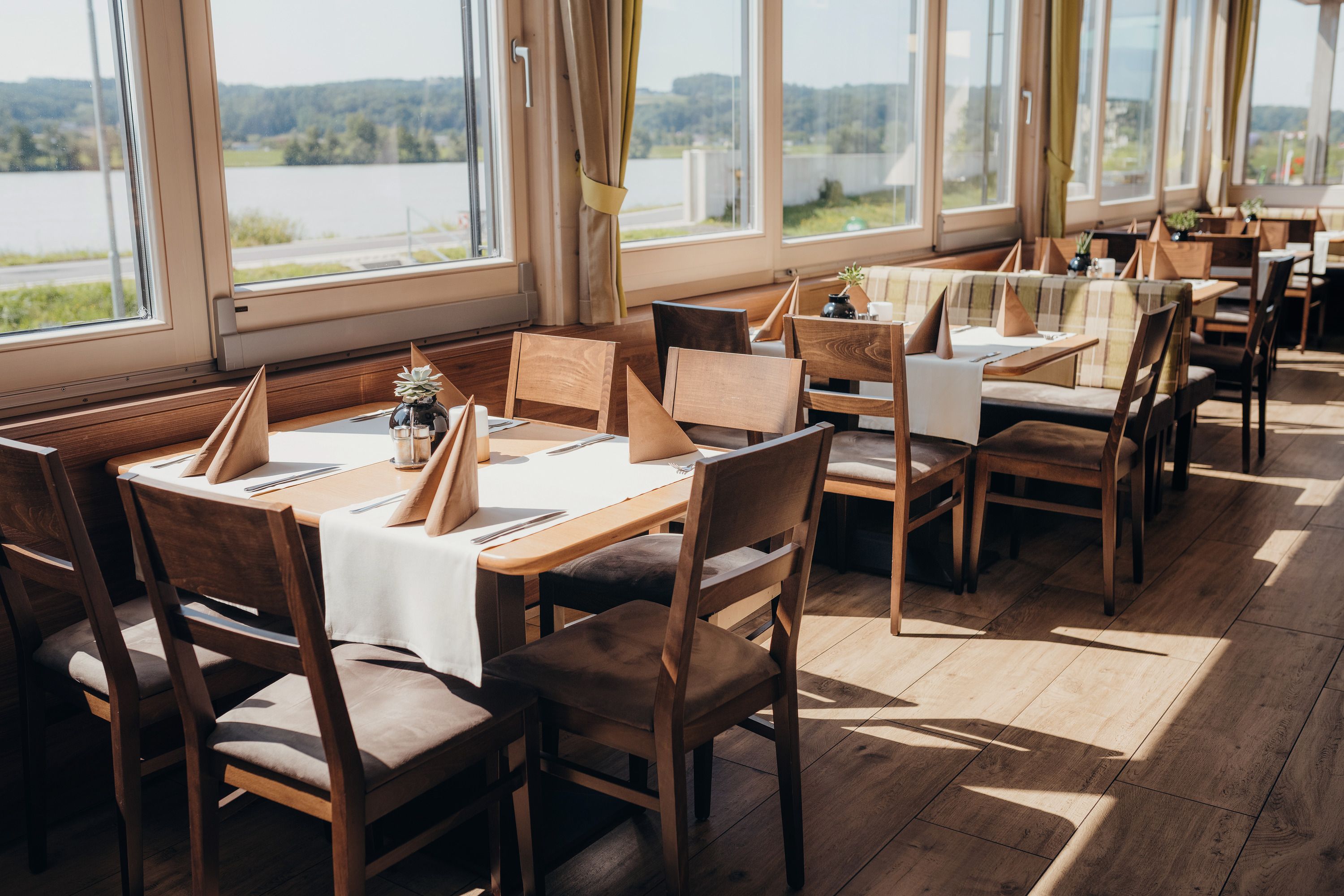 Bright restaurant with wooden furniture and a view of the Danube.