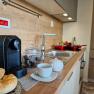 Modern kitchen with coffee machine, bread rolls and crockery on the worktop.