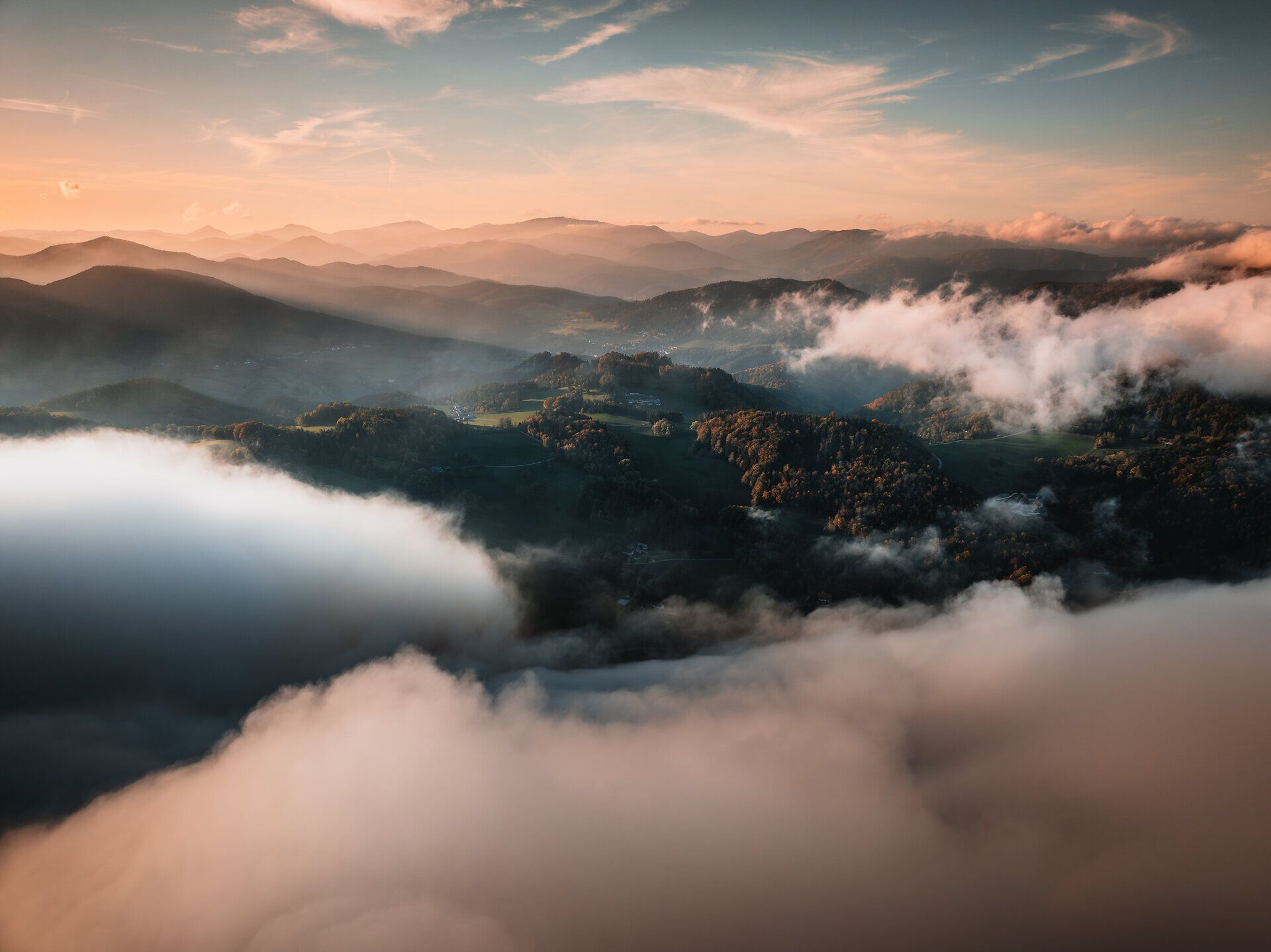 Die sanften Hügel der Wiener Alpen sind in ein mystisches Nebelkleid gehüllt, das die Landschaft in eine traumhafte Kulisse verwandelt. Die goldenen Strahlen der Sonne brechen durch die Wolken und verleihen der Szenerie eine zauberhafte Atmosphäre, die zum Verweilen und Entdecken einlädt.
