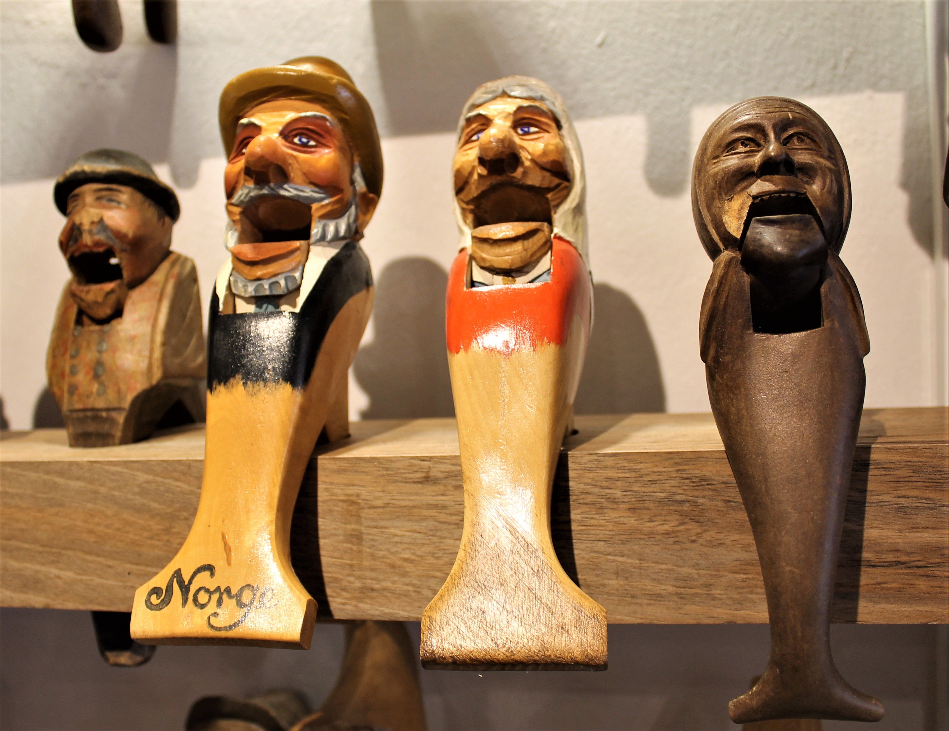Wooden carved nutcrackers in the shape of heads on a shelf.