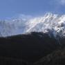 Snow-covered mountain with wooded foreground and blue sky.