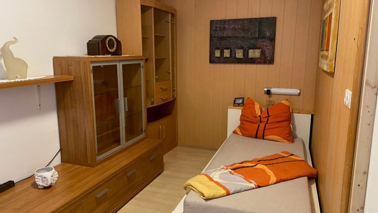 Single room with wooden furniture, single bed and decoration.