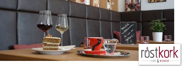 Interior view of a café with wine glasses, cakes and a blackboard on a table.