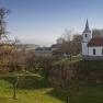 Landscape with church and trees under a clear sky.