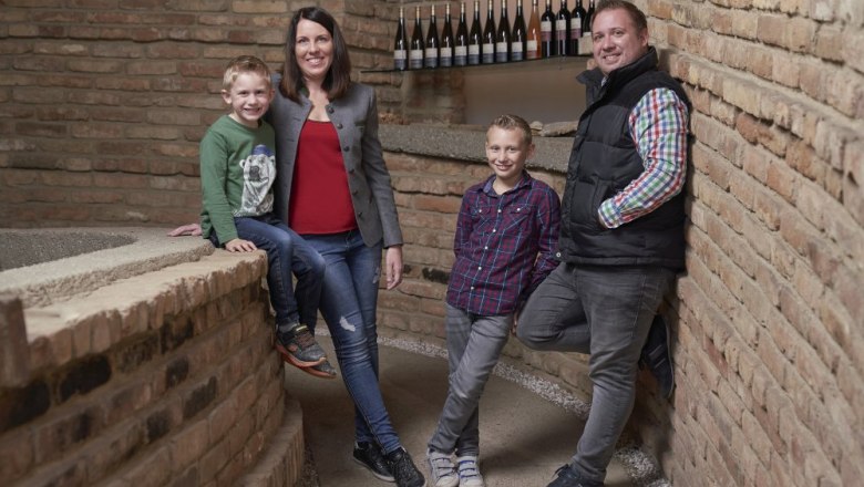 A family stands in front of a brick wall in a wine cellar.