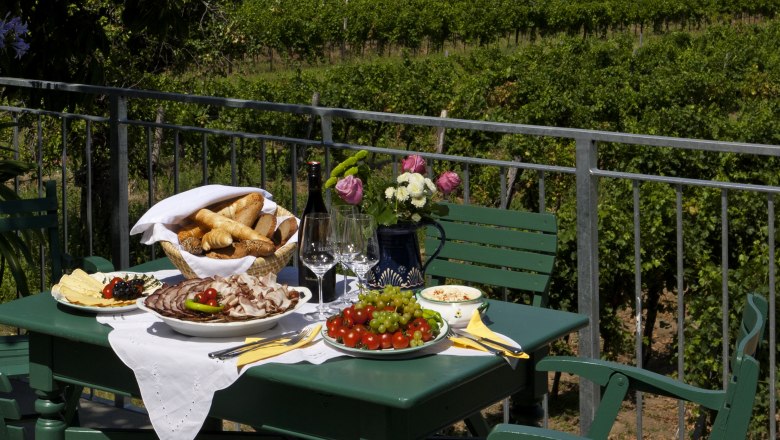 A laid table on a terrace with a view of vineyards.