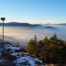 View from the Kleine Kanzel of mist-covered mountains and forests at sunrise.