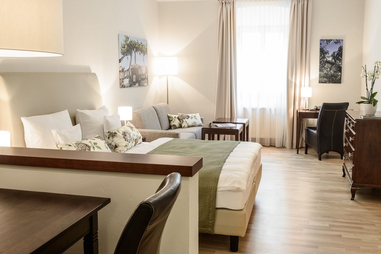 Bright, cozy hotel room with bed, sofa, desk and decoration.