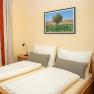 A cozy double room with a double bed, a window with curtains and a landscape painting on the wall.