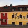 Facade of the Bergwirt Schrammel & Mohnhotel with red and yellow paint.