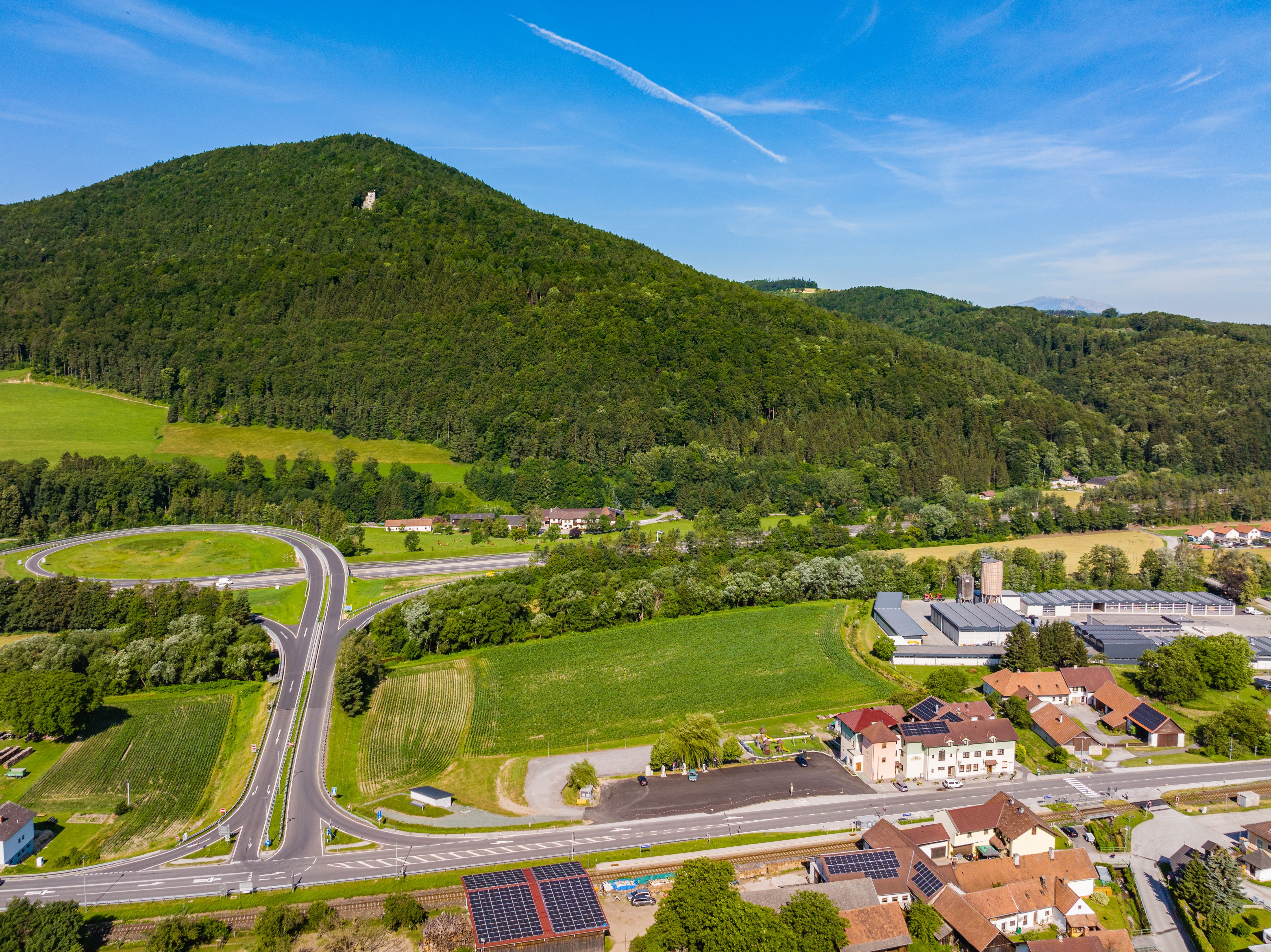 Aerial view with fields and the forested Kulmriegel with Grimmenstein Castle in front of the highway exit and Gasthof Pichler.