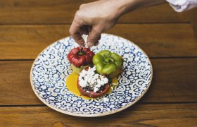 A plate of stuffed peppers, decorated with cheese, on a wooden table.