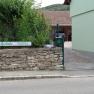 Entrance to Haus Gerlinde with sign and stone wall.