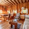 Rustic living and dining area with wooden furniture, wooden walls and hunting trophies on the wall.