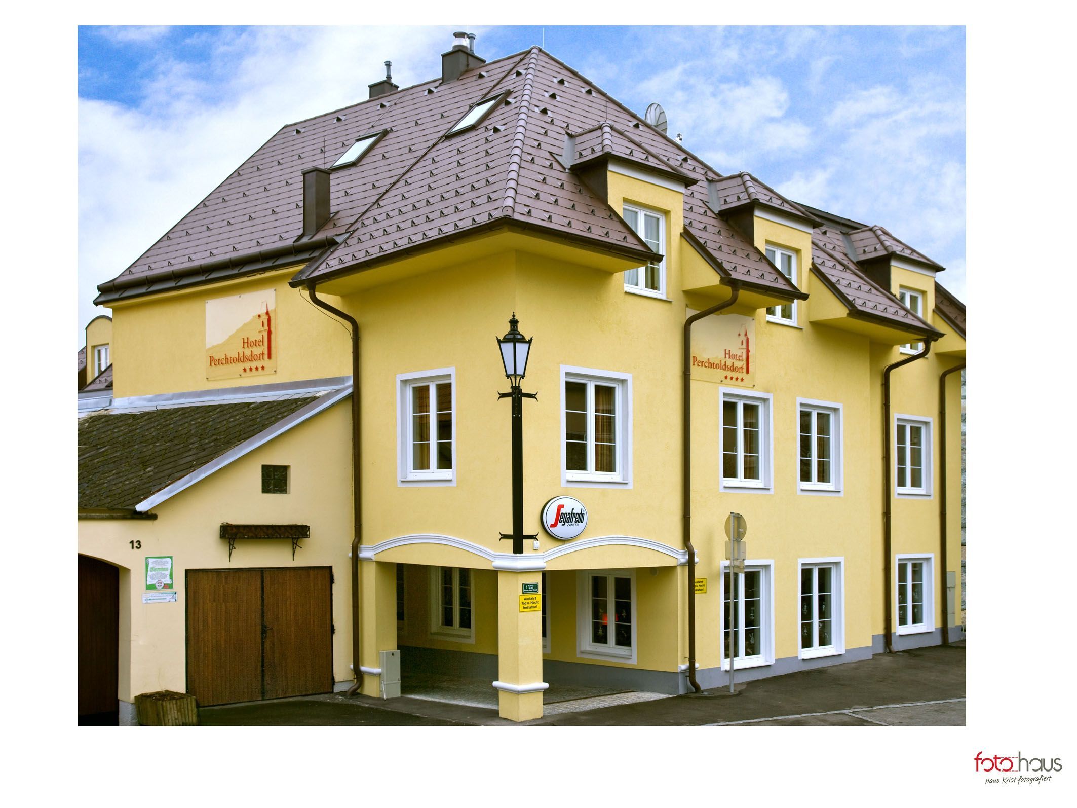 Yellow hotel building with several windows and a sign with the inscription 'Hotel Perchtoldsdorf'.