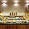 A breakfast buffet with bread rolls, cold cuts, muesli, fruit and drinks on a wooden counter.