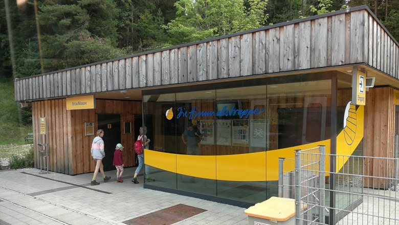 Erlaufklause station with wooden fa&ccedil;ade and glass front, people entering the building.