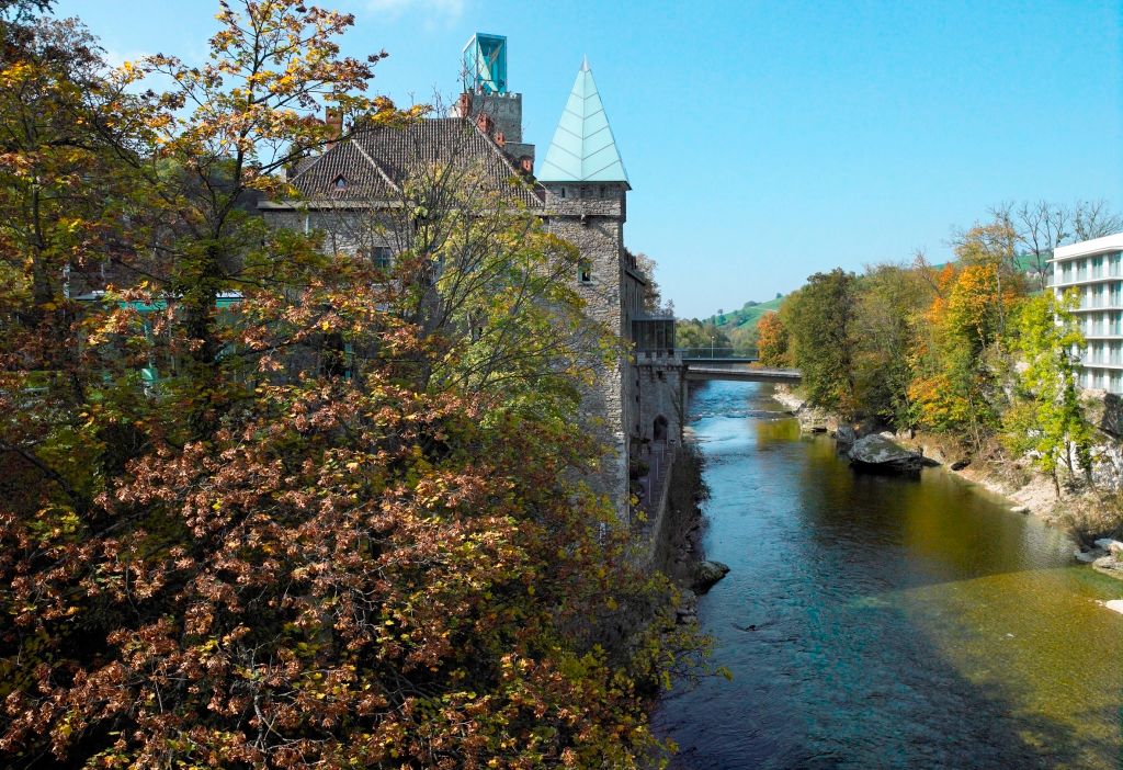 River with fall trees and buildings in the background.