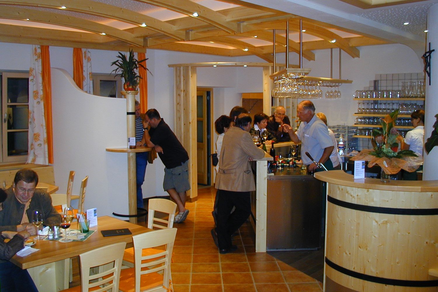 Interior view of a wine tavern with guests at the bar and at tables.