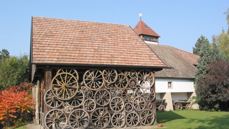 A building with a fa&ccedil;ade made of old wagon wheels, surrounded by trees and a lawn.