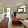 Modern eat-in kitchen with fitted kitchen, dining table, TV and red seating furniture.