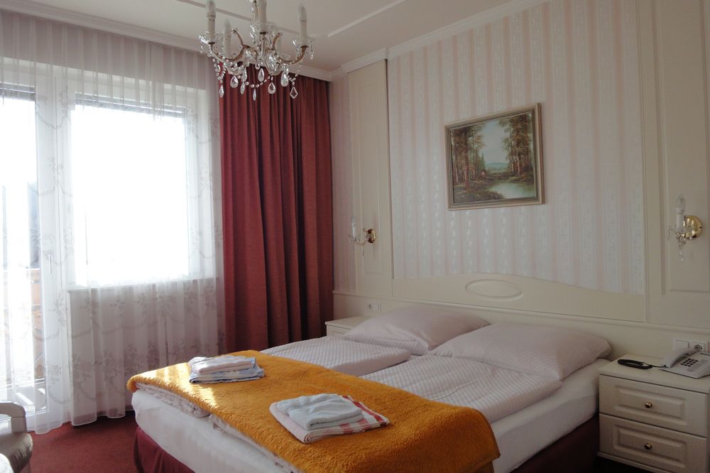 Hotel room with double bed, chandelier and painting on the wall.