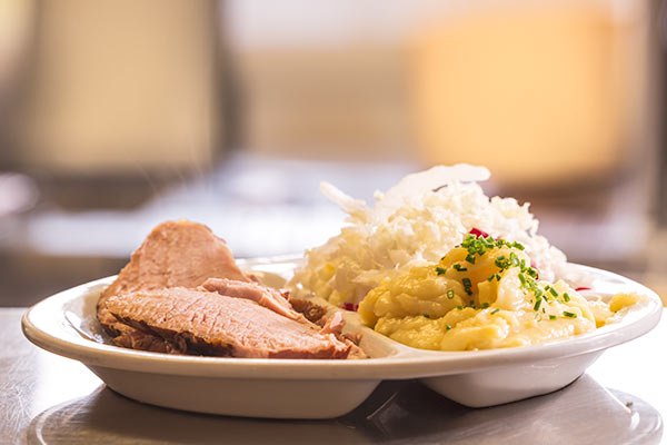 A plate of meat, sauerkraut and mashed potatoes.