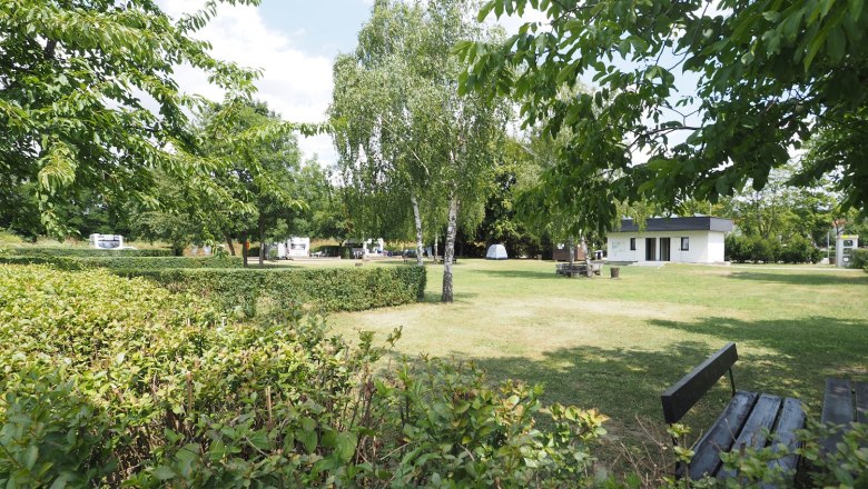 Stellplatz auf einer frisch gemähten Wiese. Om Hintergrund ein Häuschen für Sanitäranlage.