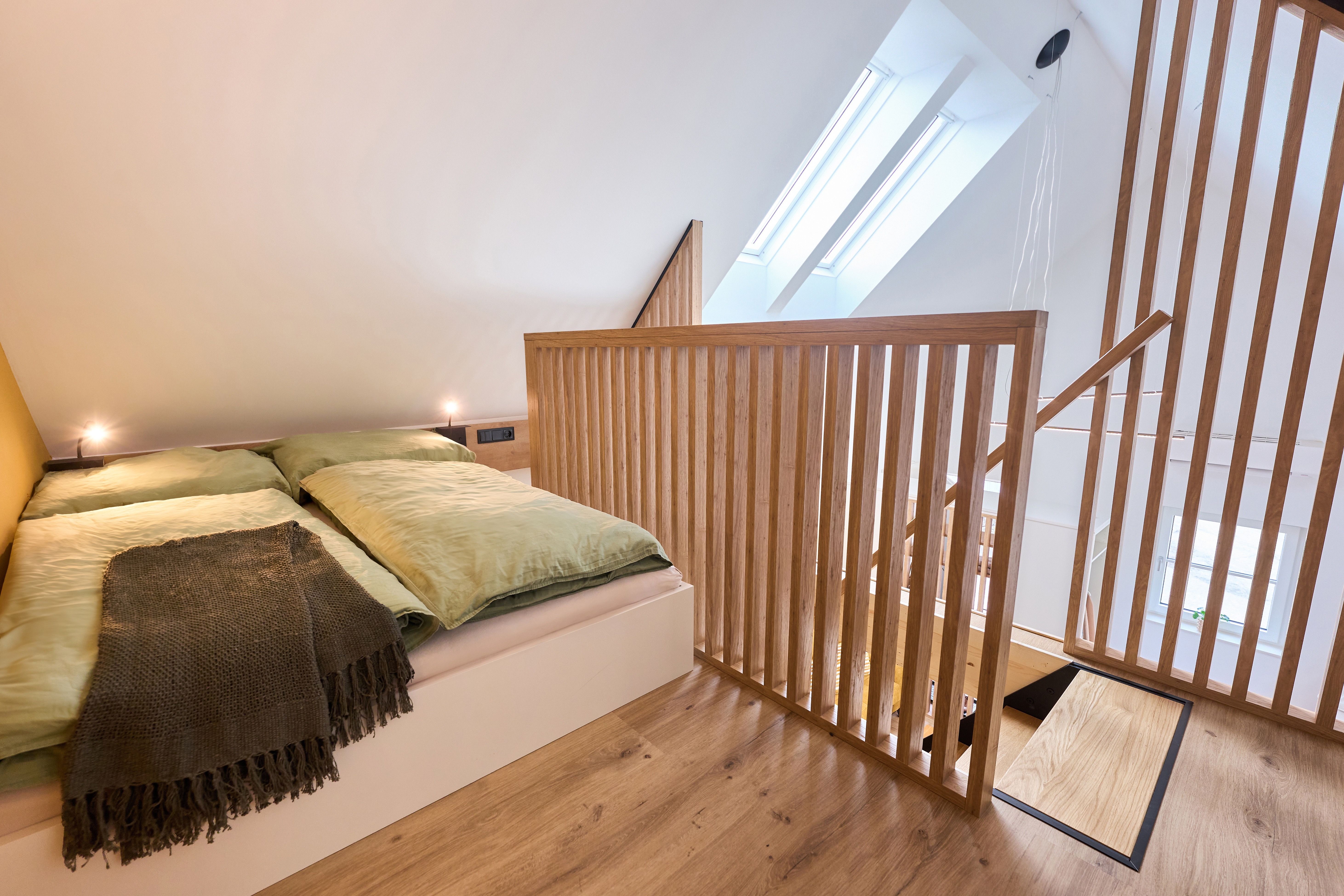 Modern bedroom in the attic with wooden railings and skylights.