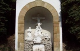 A small chapel with a cross and religious figures in a niche.