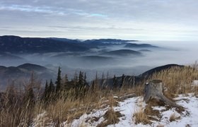 View from Otter of mist-shrouded mountains and valleys with snow-covered ground in the foreground.