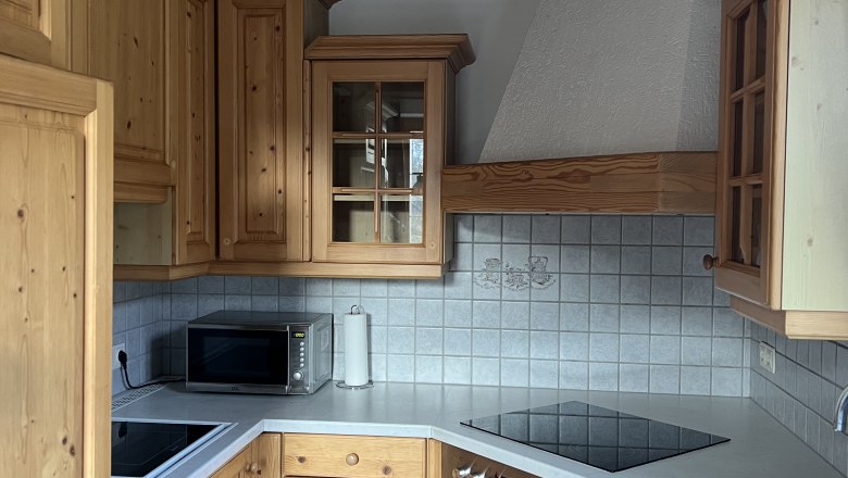 Kitchen with wooden units, stove, sink and microwave.