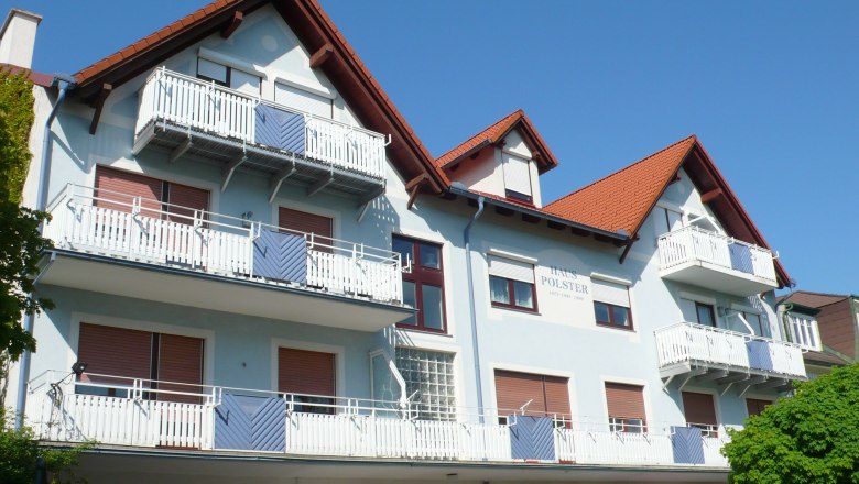 Multi-storey building with blue fa&ccedil;ade and red roofs.