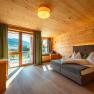 Hotel room with wooden walls, large bed and balcony with mountain view.