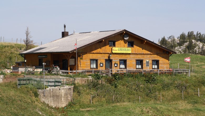 A traditional wooden building in an alpine landscape with the inscription 'Almreserhaus'.