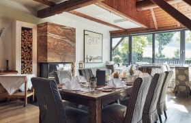 Elegant restaurant with wooden beams, fireplace and covered tables.