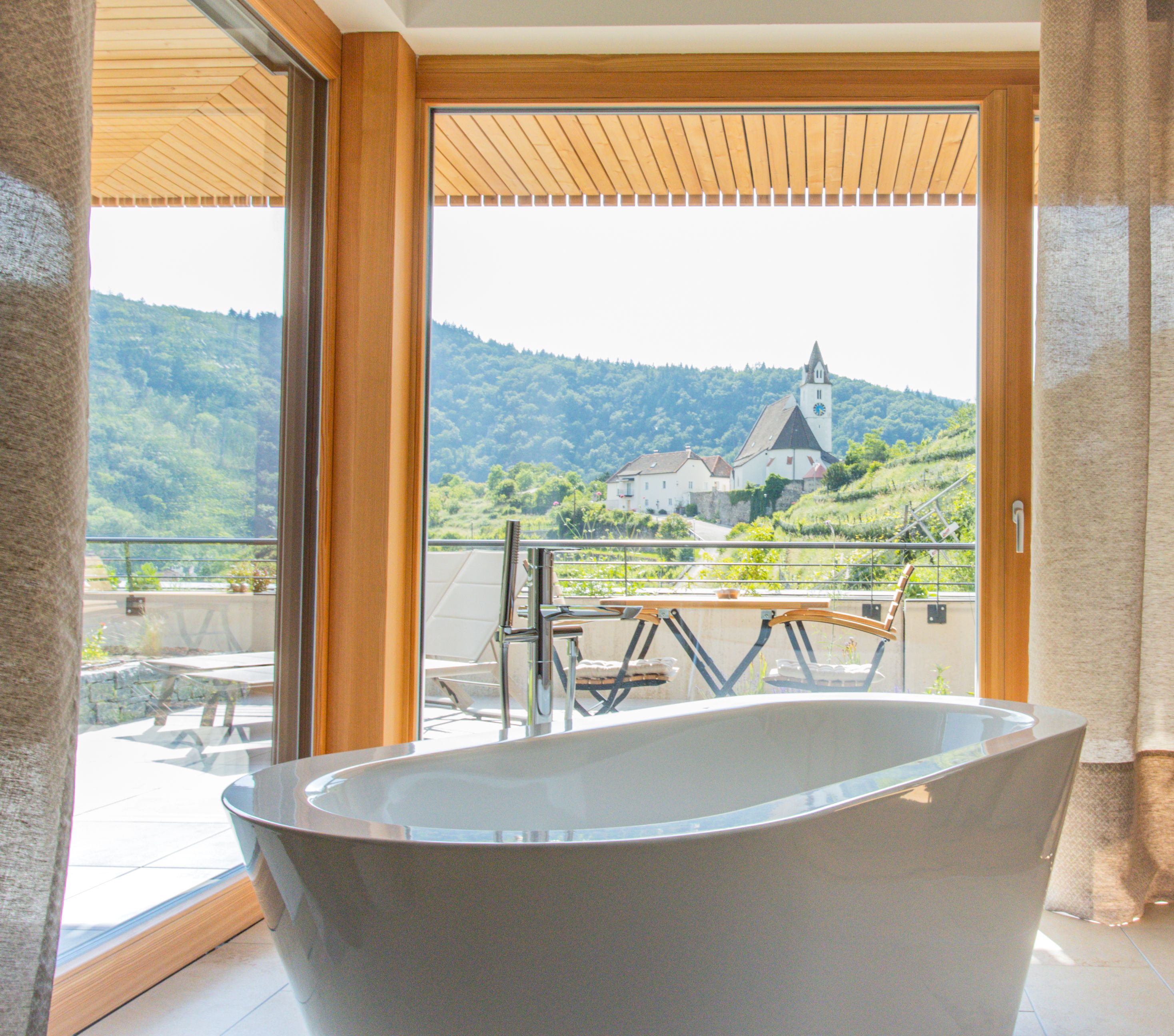 Aerial view of a modern hotel with terraces and green roofs, surrounded by vineyards.